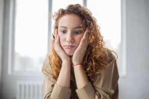 A young woman rests her head in her hands and looks overwhelmed